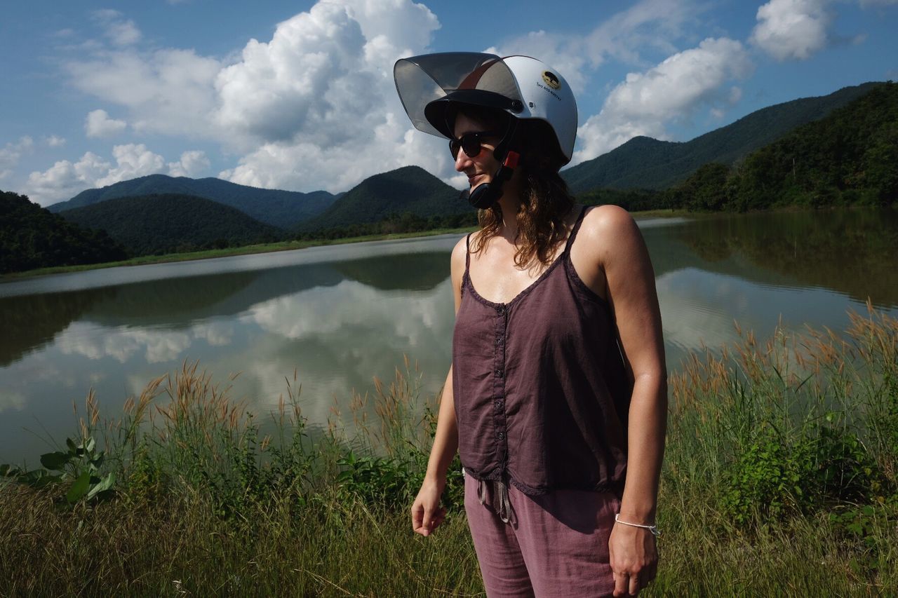 Woman wearing helmet while standing at lakeshore