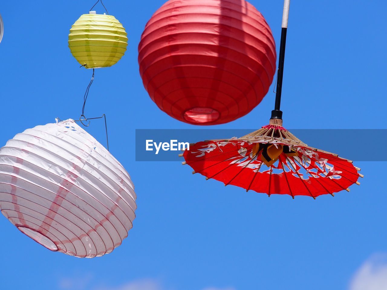 Low angle view of lanterns hanging against blue sky