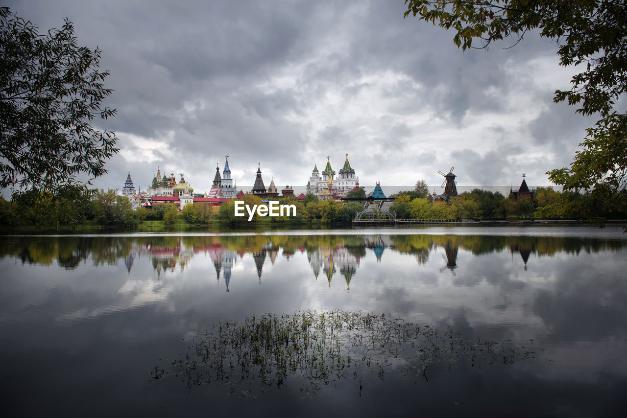 Reflection of trees in lake against cloudy sky