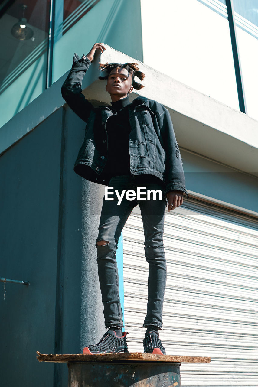 Full length of young man standing against wall