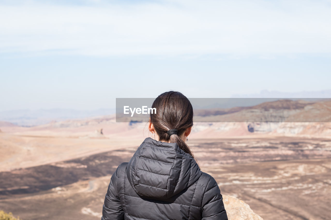 Rear view of woman standing on arid landscape