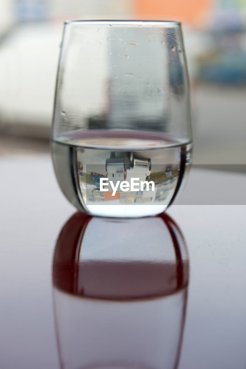 CLOSE-UP OF REFLECTION OF DRINKING GLASS ON TABLE