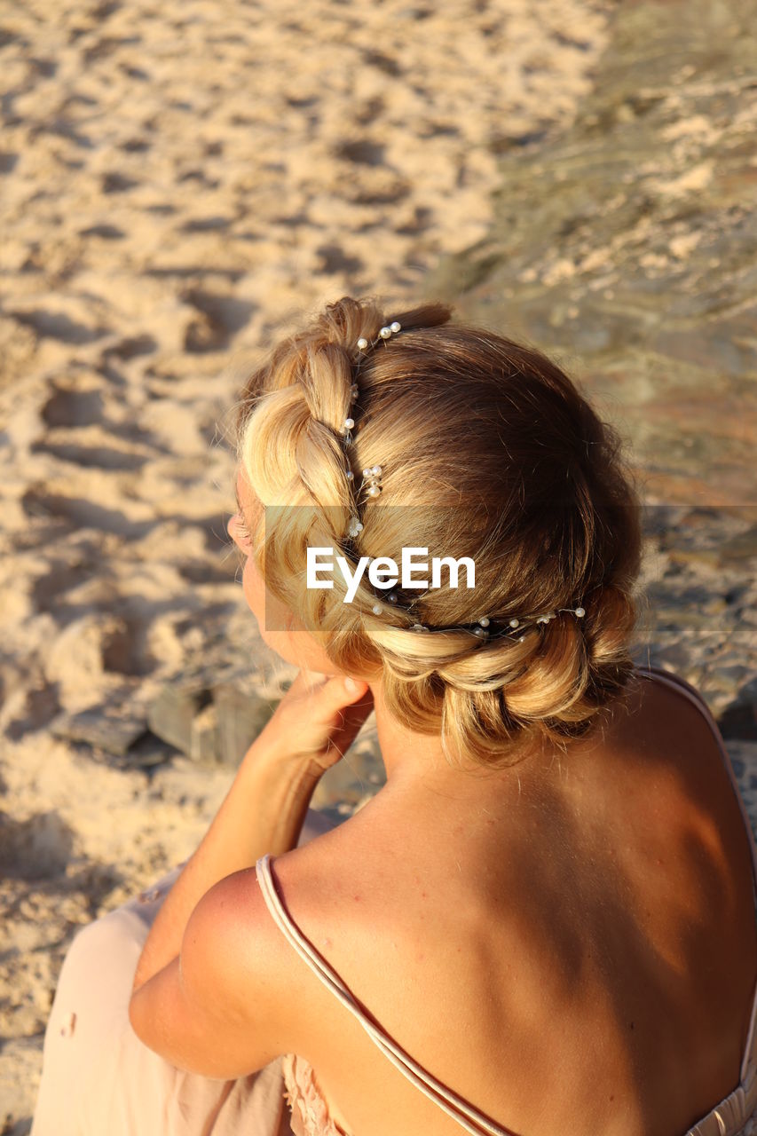 REAR VIEW OF WOMAN WITH ARMS RAISED ON BEACH