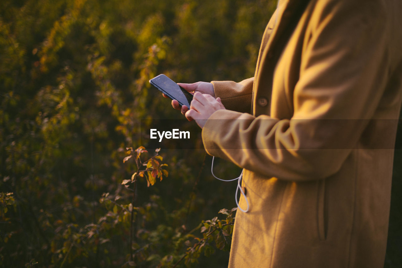 Midsection of woman using phone while standing outdoors