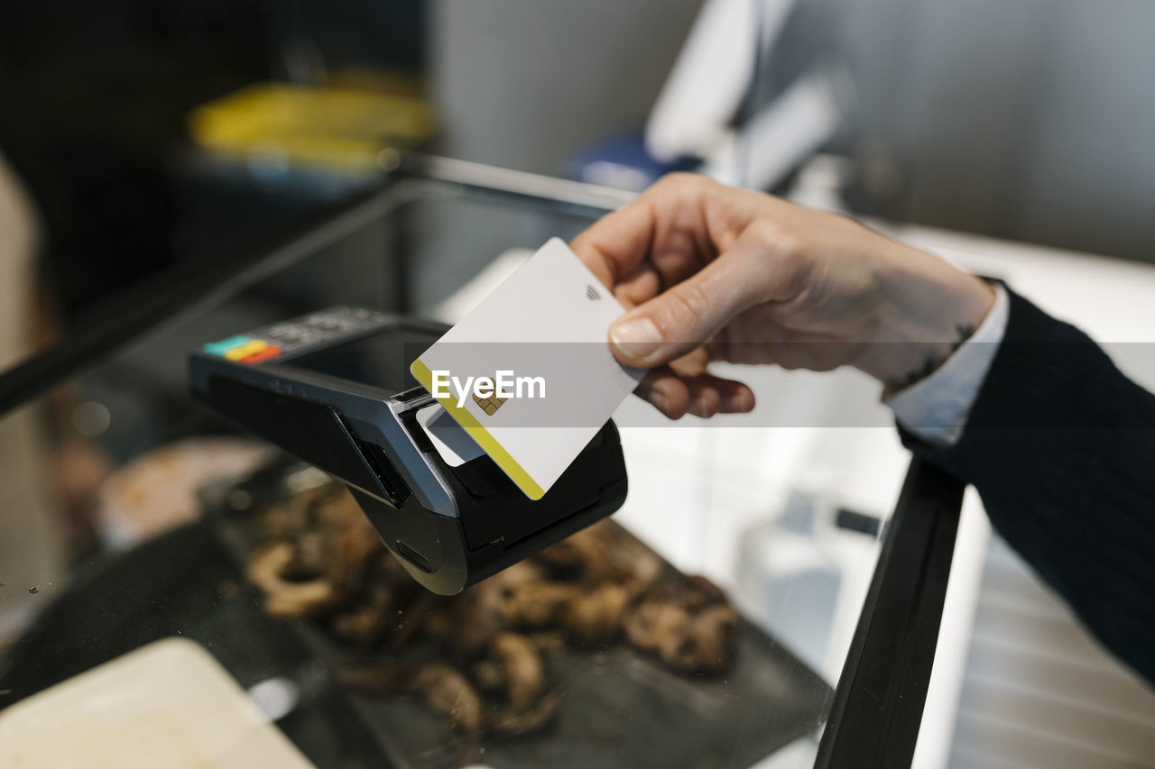 Female customer making payment through credit card in illuminated restaurant