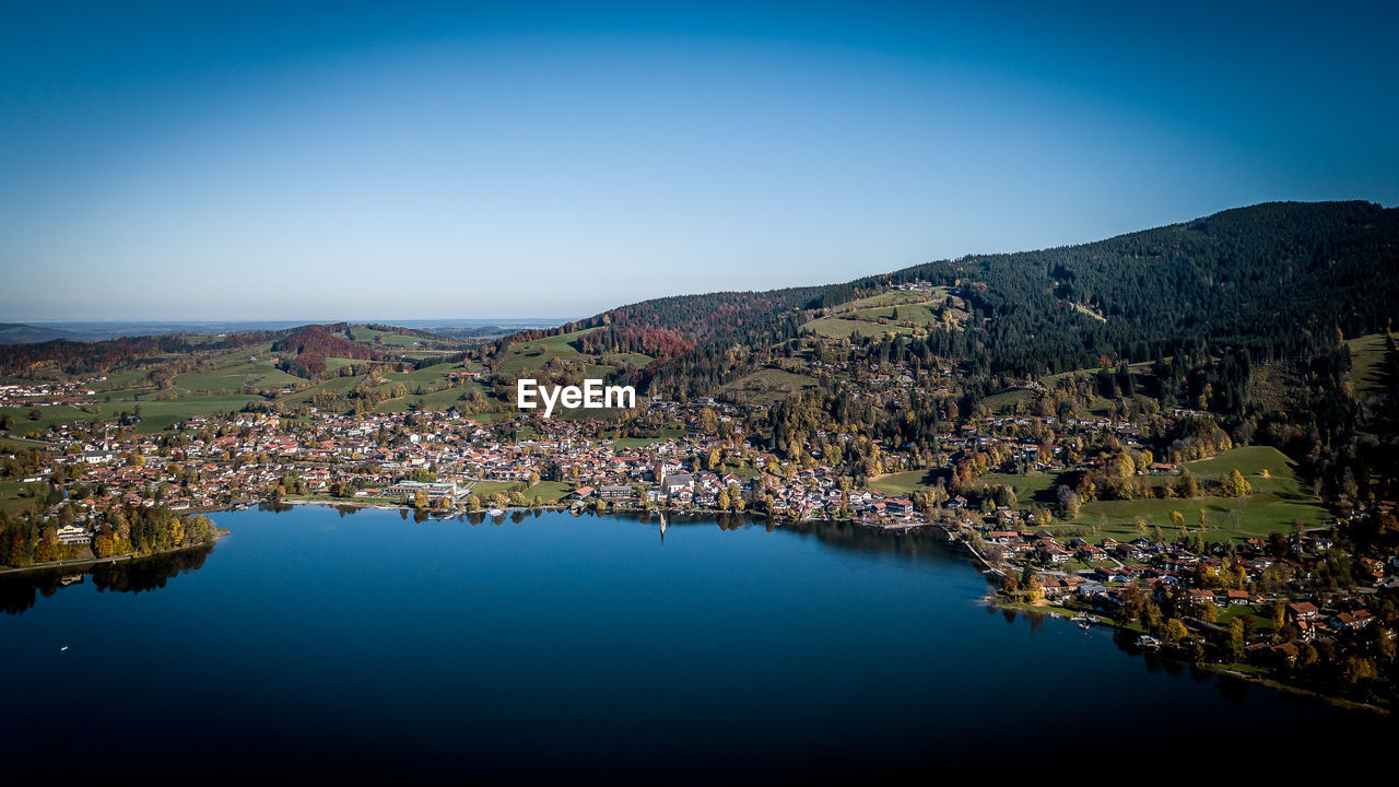 Scenic view of lake and mountains against clear blue sky