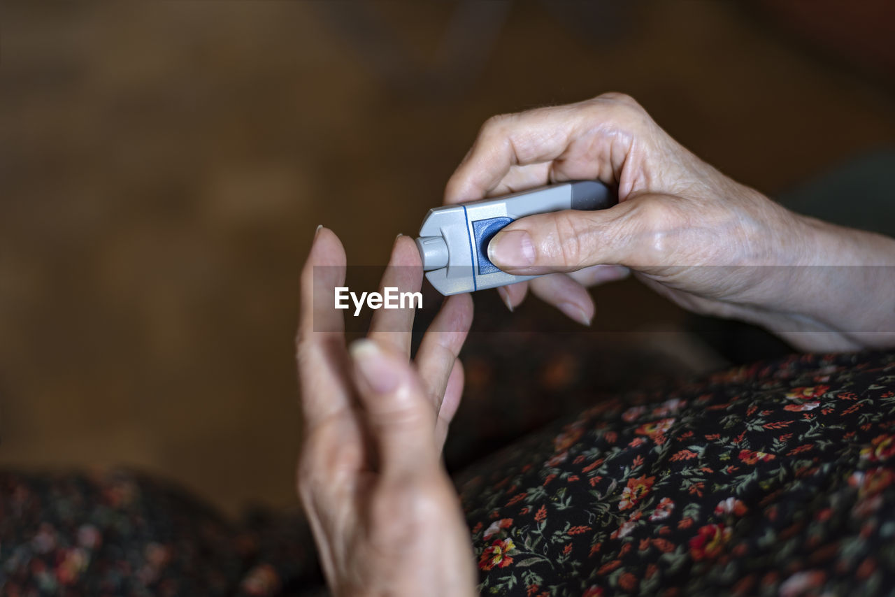 Cropped hands of woman checking blood sugar