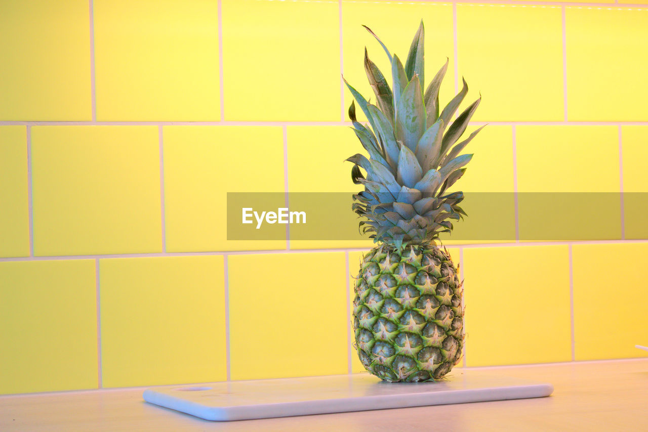 Pineapple against wall on table