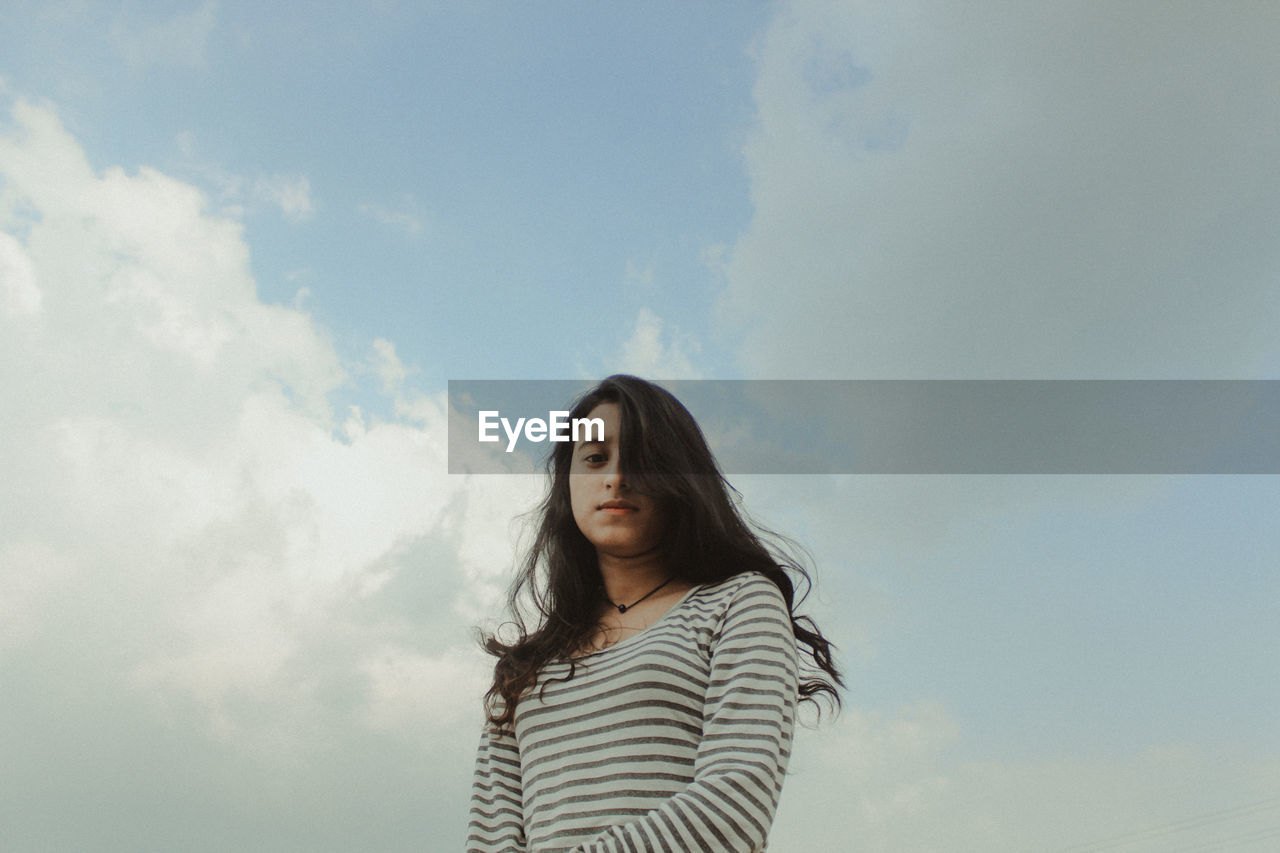 BEAUTIFUL WOMAN STANDING AGAINST SKY