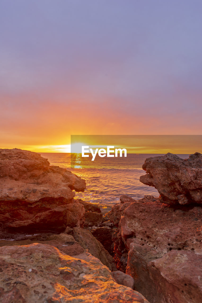 SCENIC VIEW OF ROCKS AT SUNSET