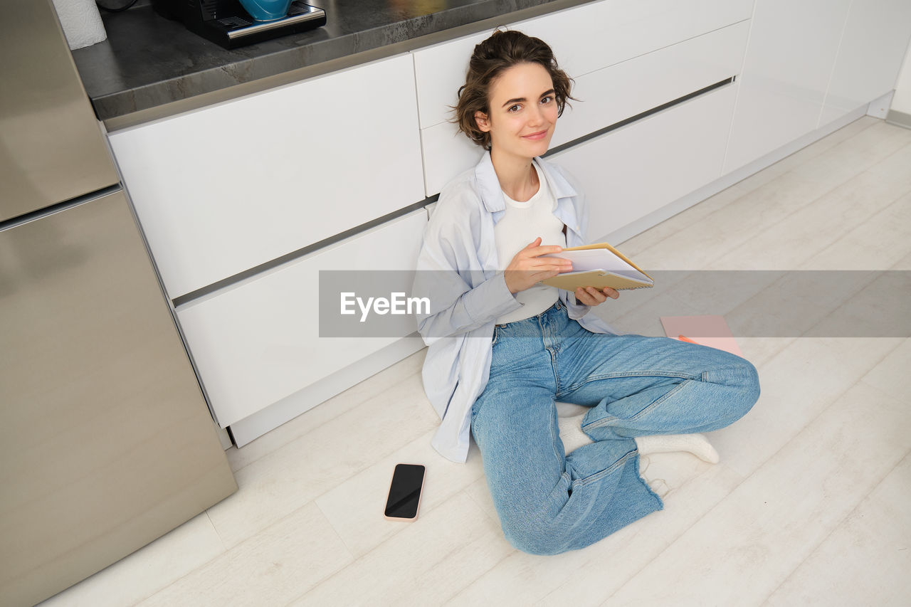 low angle view of young woman sitting on floor at home
