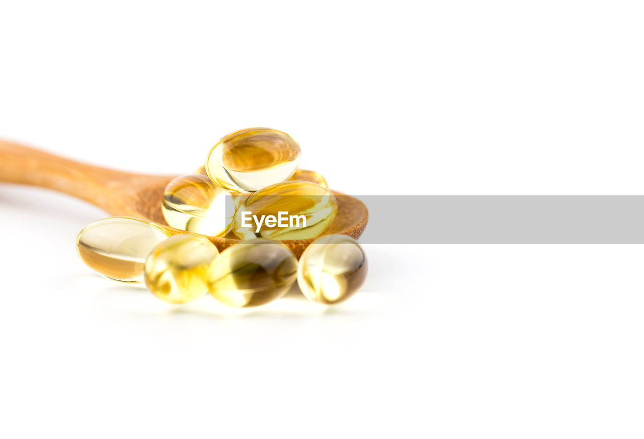 Close-up of medicines with wooden spoon on white background