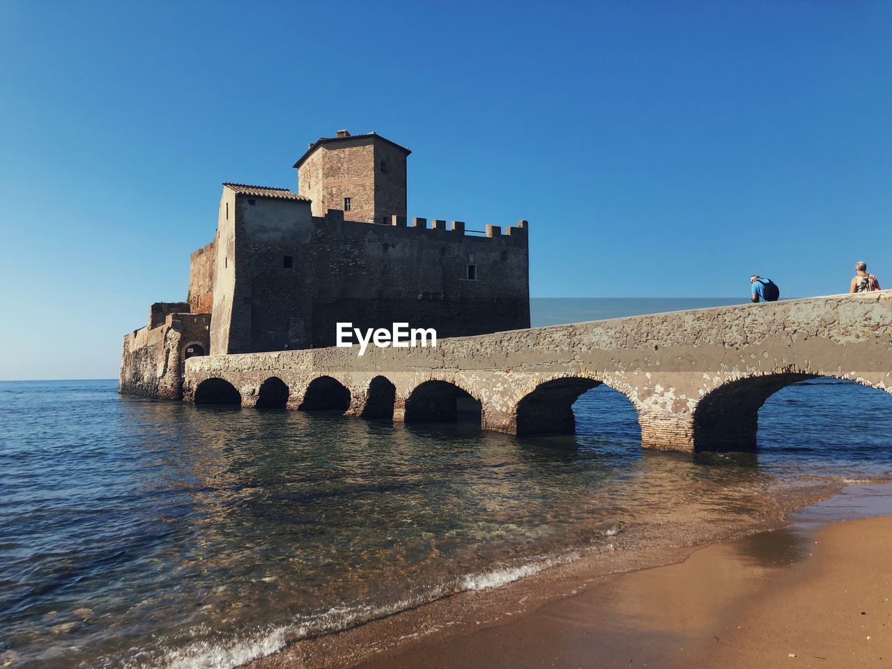 Bridge over sea against clear blue sky