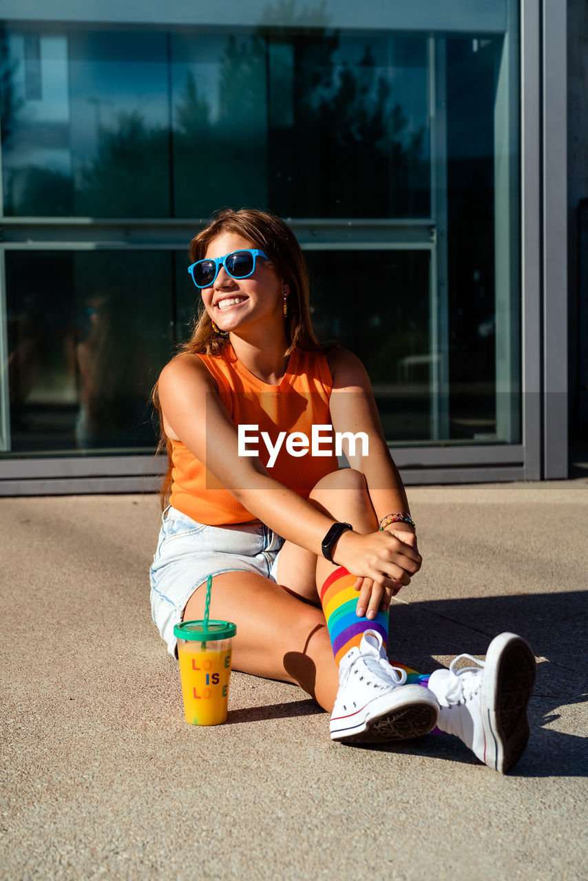 Happy  teen girl in bright colorful top, rainbow socks and sunglasses . trendy teenager generation z 