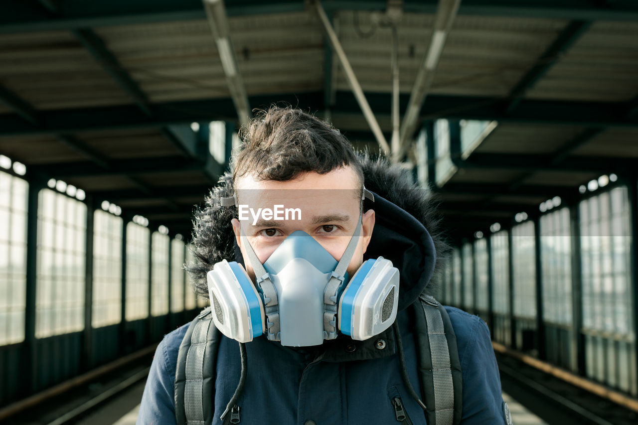 Portrait of young man at railroad station with mask on 