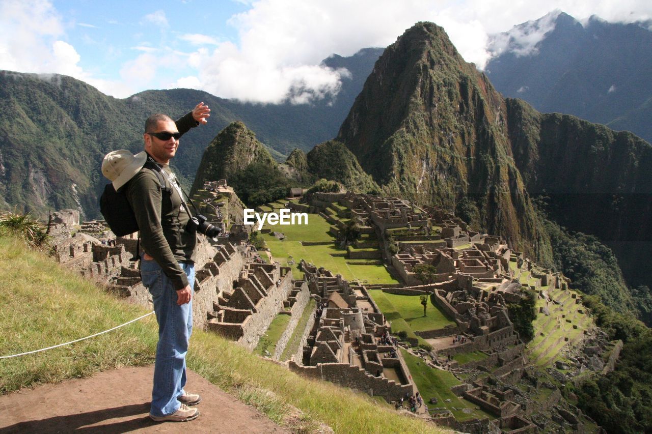 Side view of man standing on mountain against sky