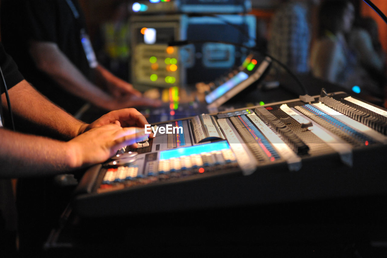 Midsection of men operating sound recording equipment in club