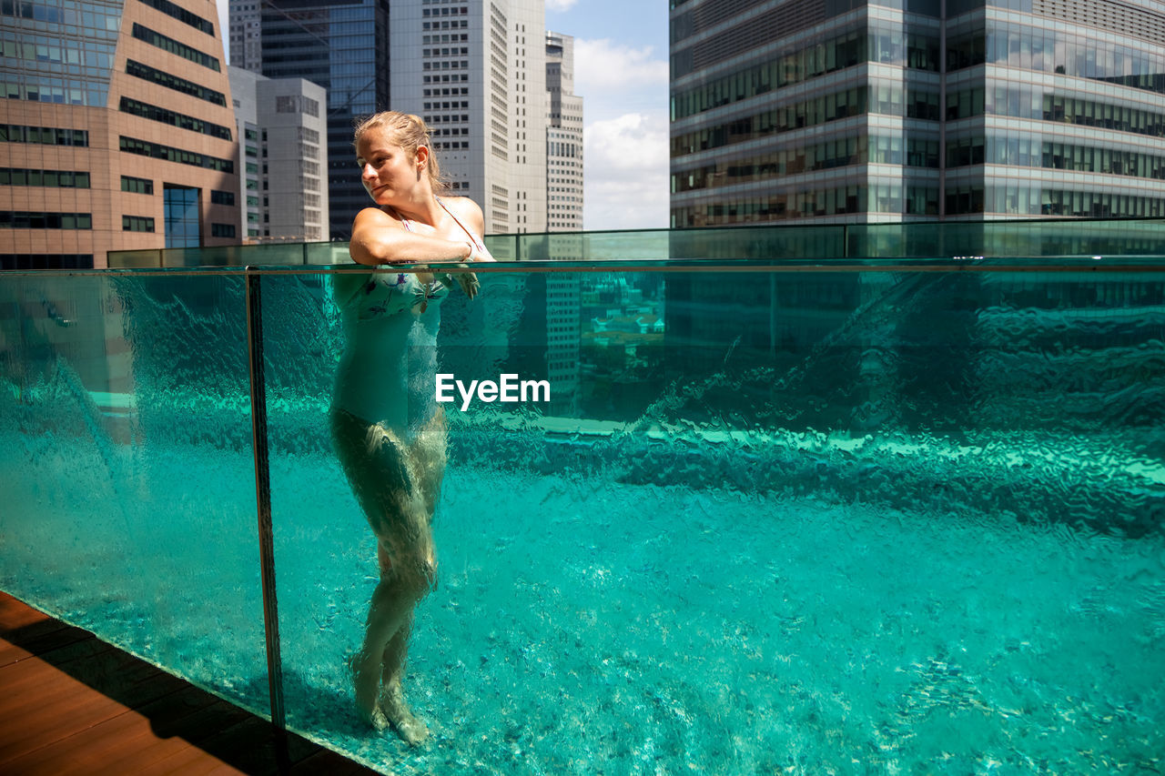 Beautiful woman resting in the pool against the background of the cityscape