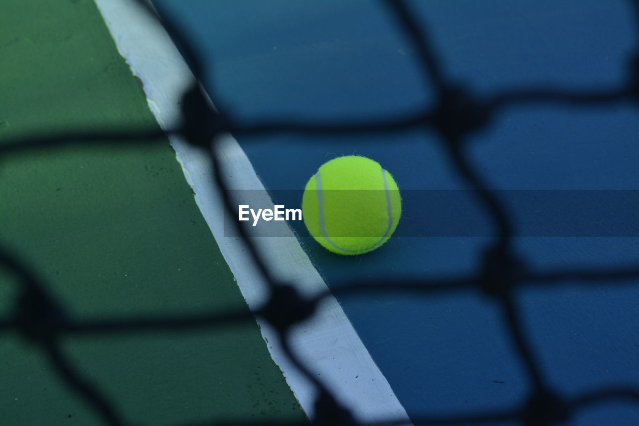 High angle view of tennis ball seen through net on sports court