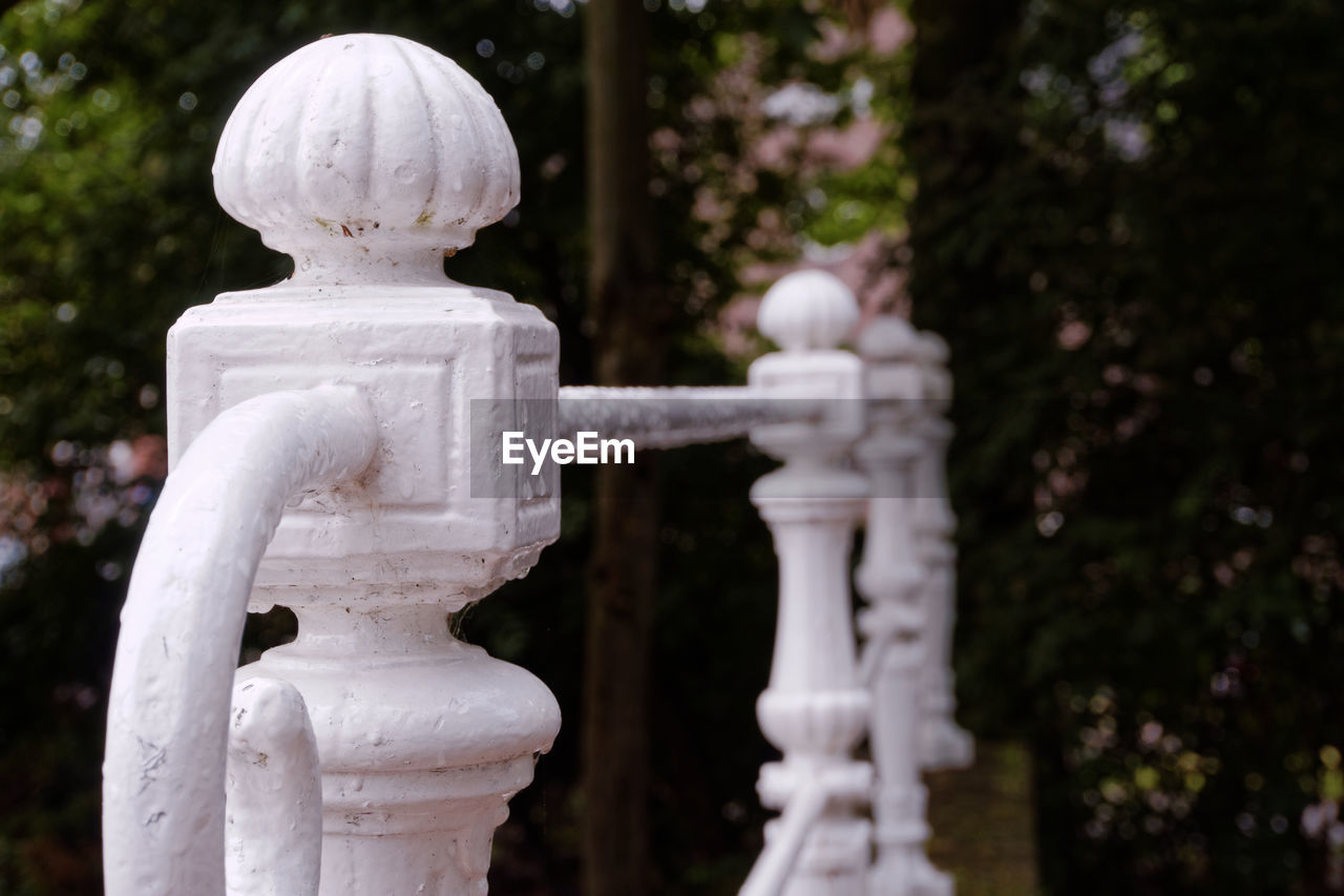 Close-up of white railing against trees
