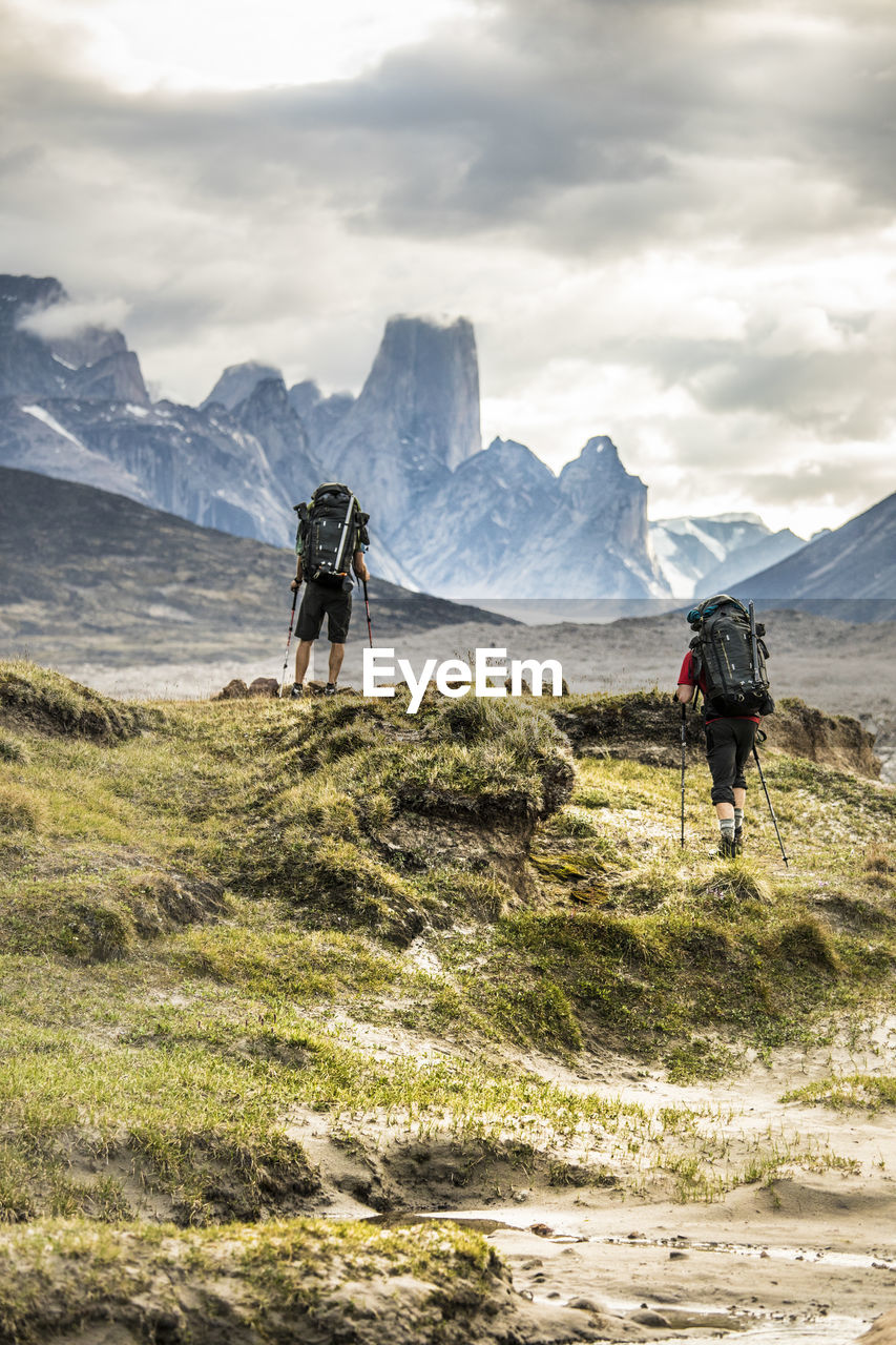 Two climbers hike through dramatic mountain pass.
