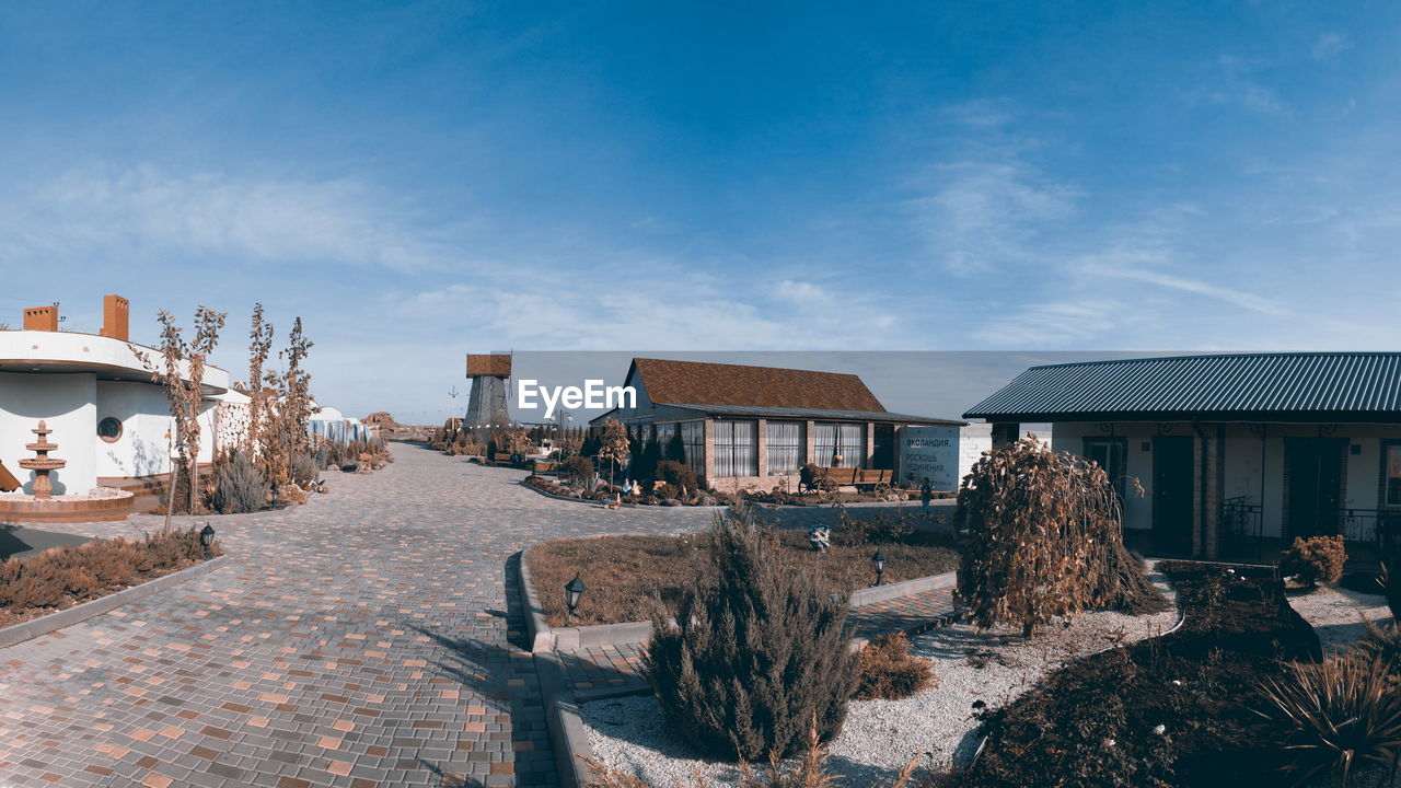 HOUSES BY BUILDINGS AGAINST SKY