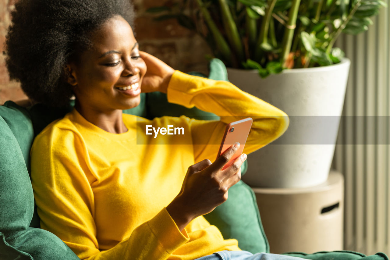 Woman using mobile phone while sitting at home