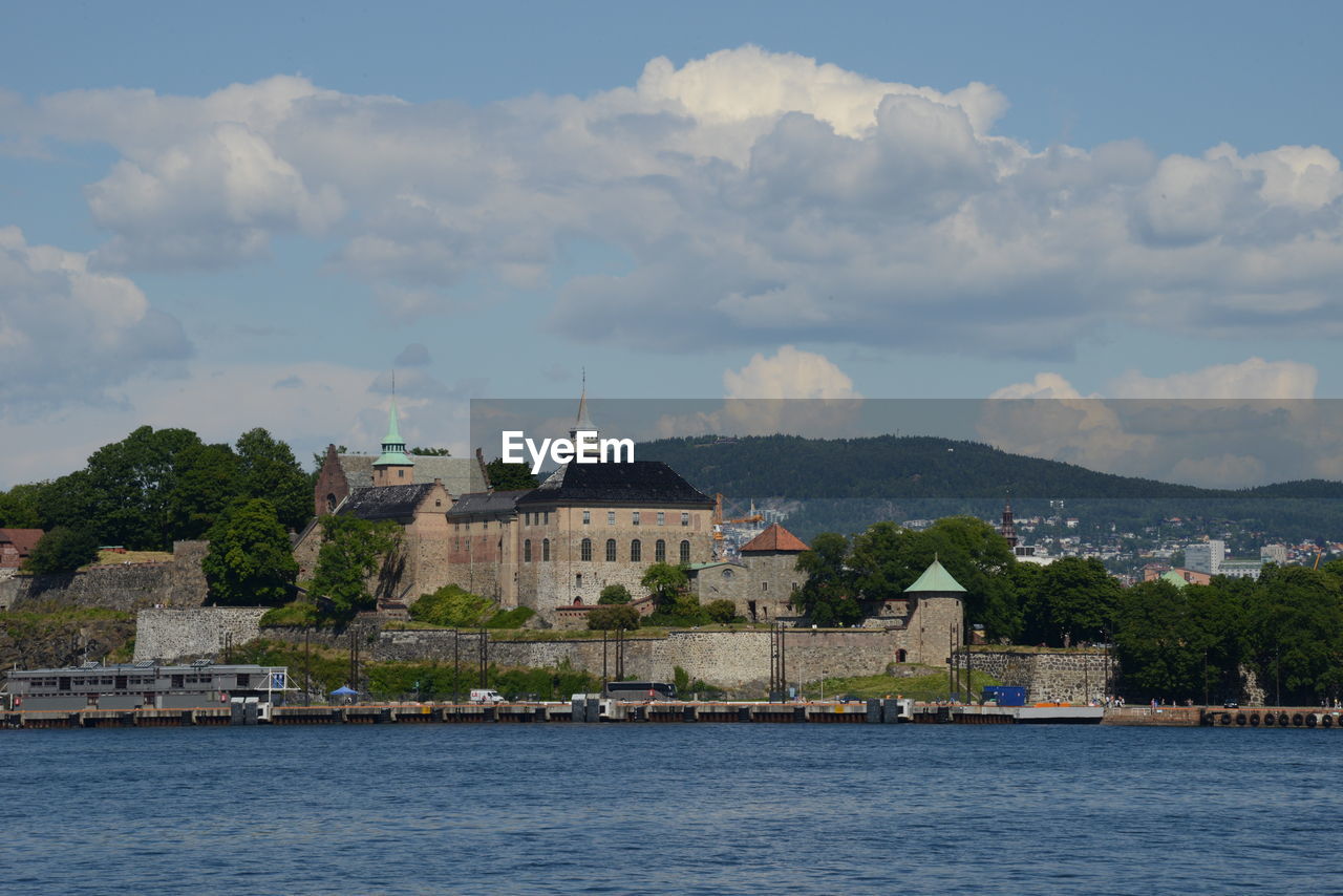 Buildings by sea against sky in city