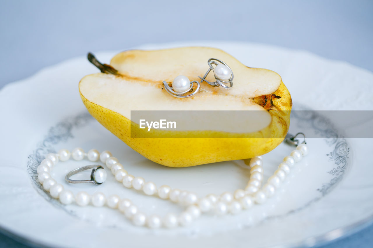 Close-up of jewelry and fruit in plate on table