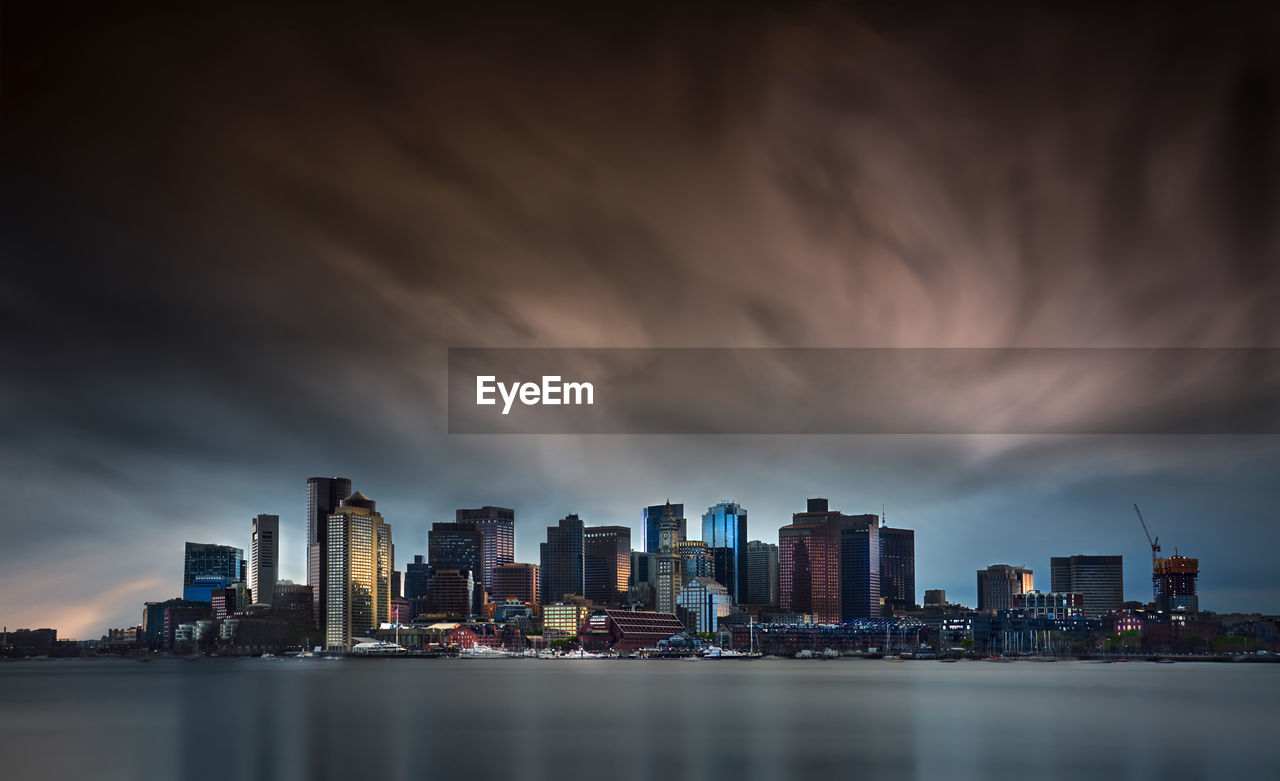 View of modern buildings in city against dramatic sky