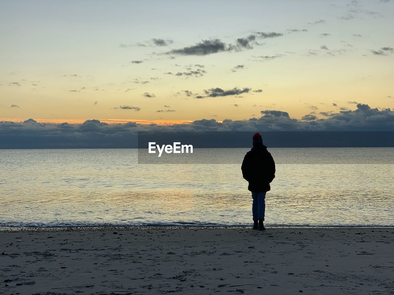 REAR VIEW OF MAN STANDING ON BEACH