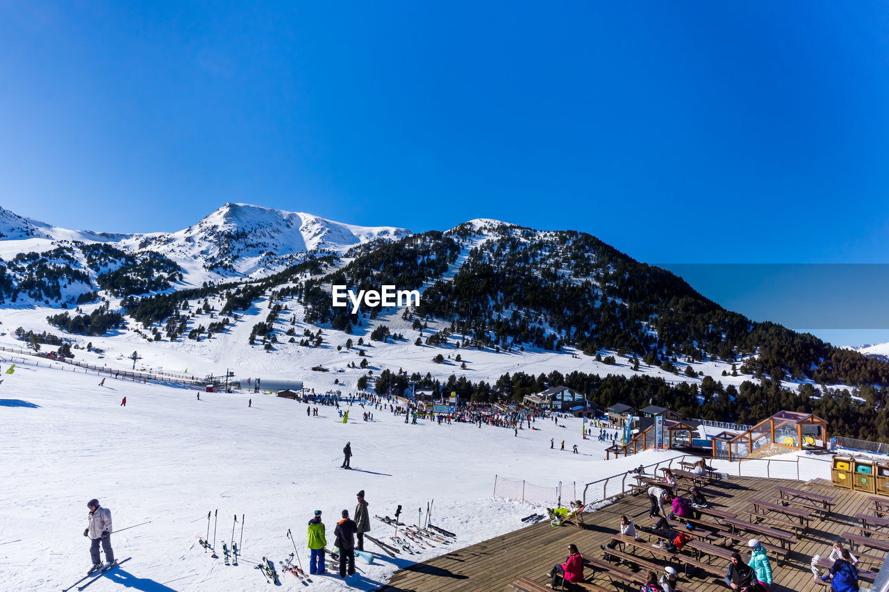 PEOPLE ON SNOWCAPPED MOUNTAINS AGAINST BLUE SKY