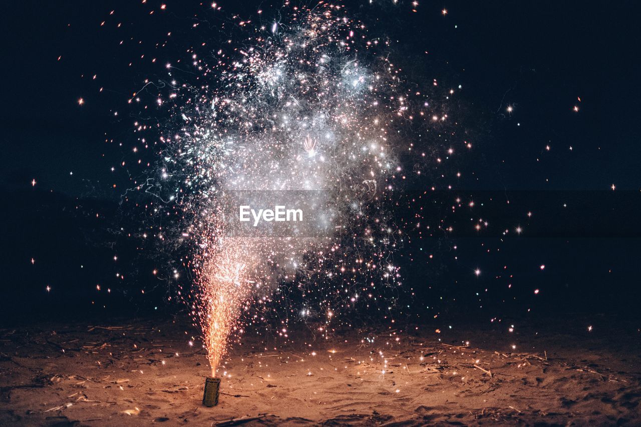 Burning firework at beach during night