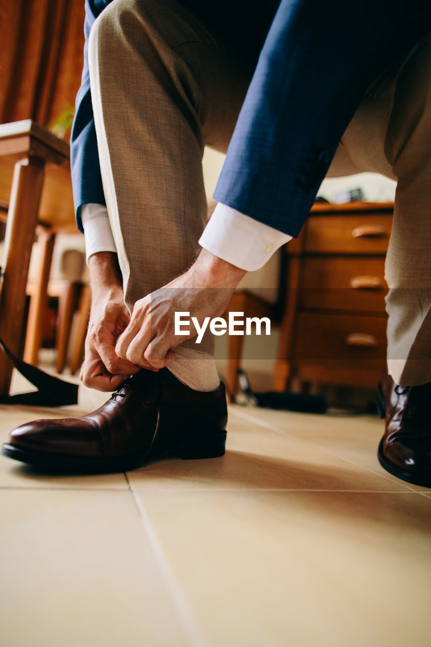 Low section of man wearing shoe on floor