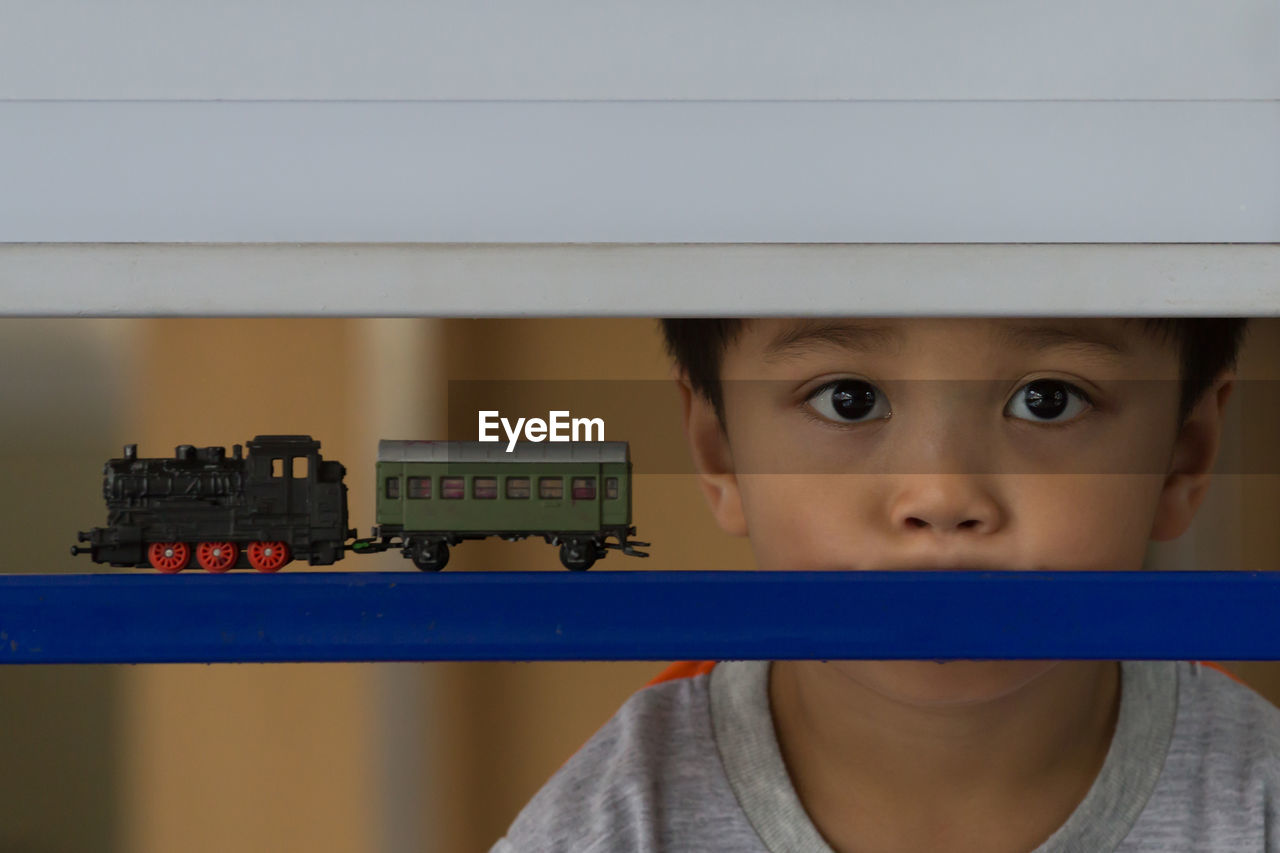 Close-up portrait of boy looking through railing