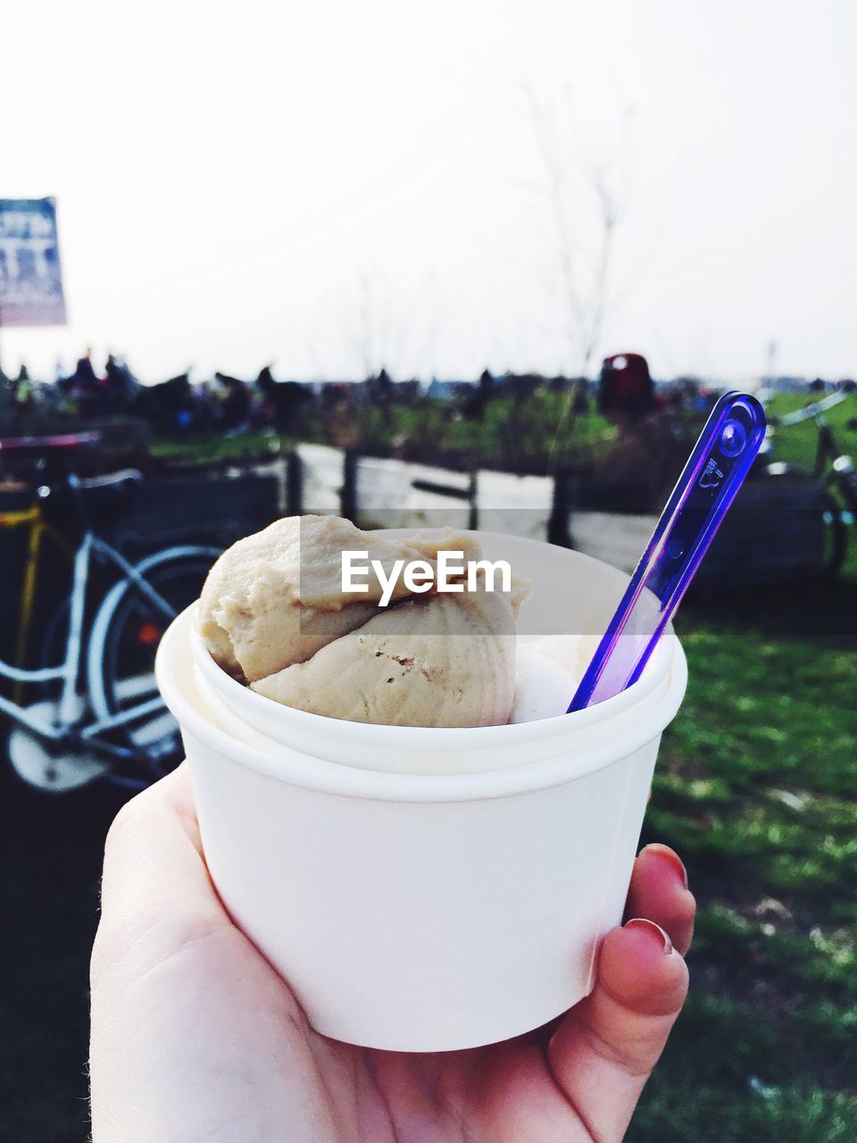 Cropped image of person holding ice cream against sky