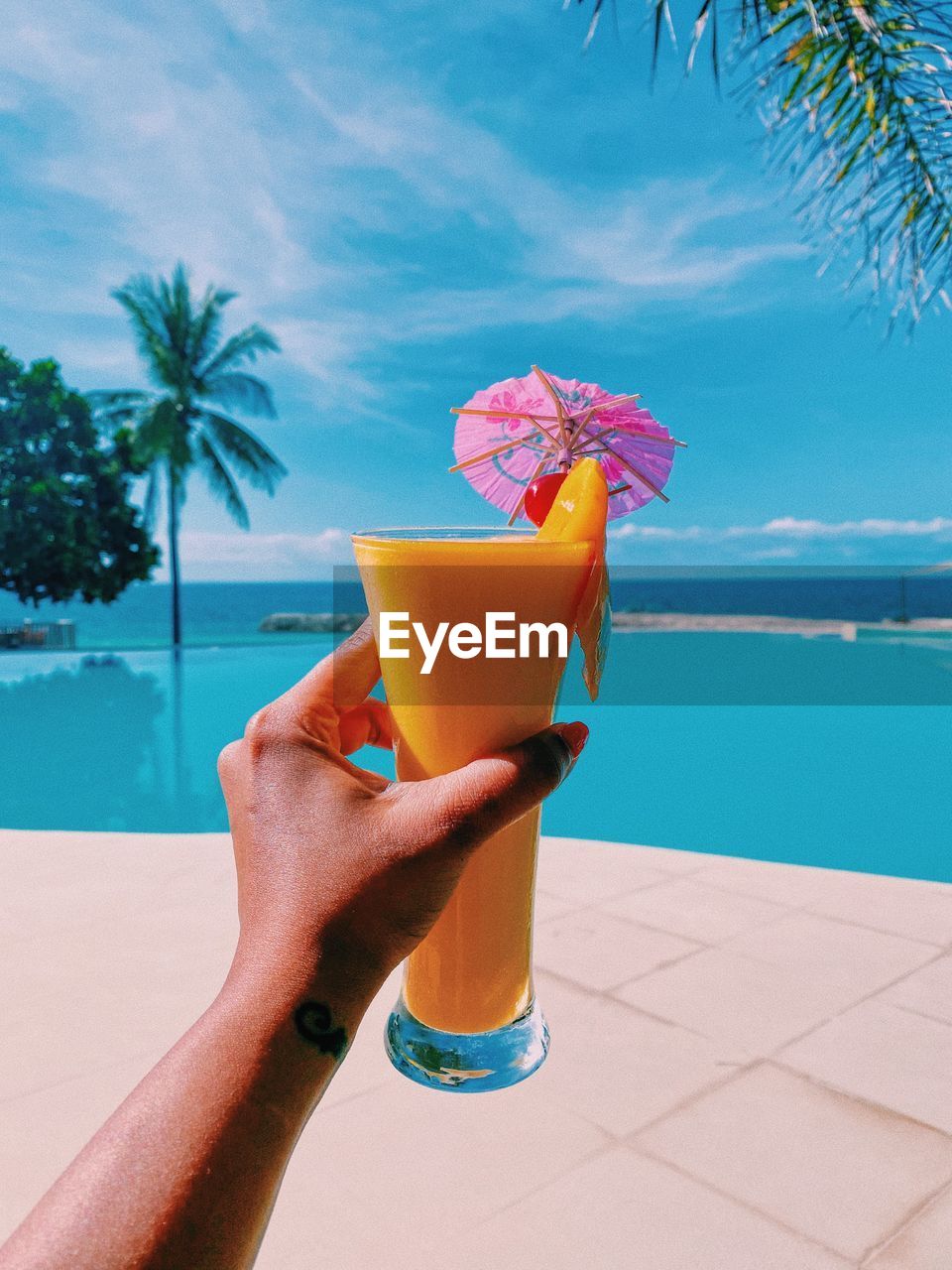 Hand holding drink at swimming pool