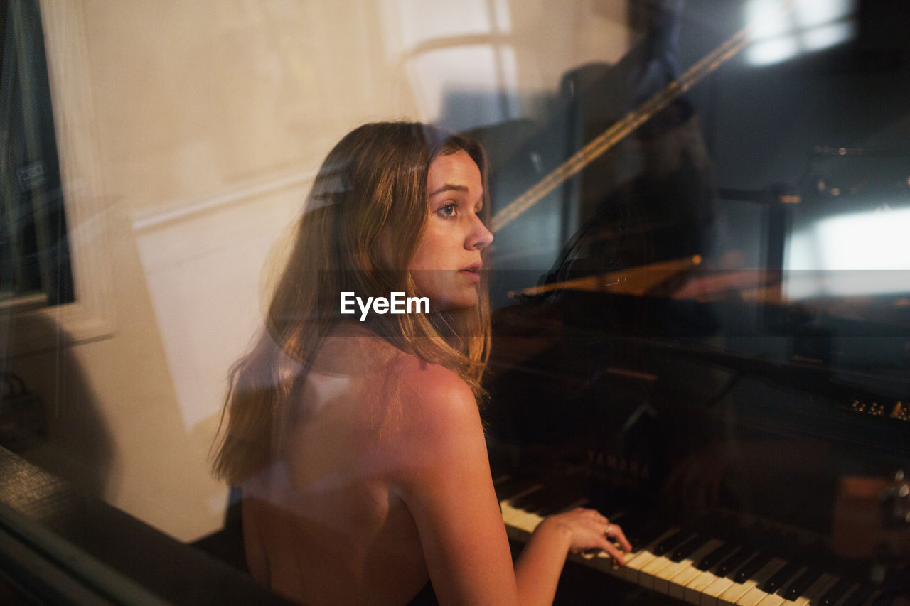 Young woman playing piano at a recording studio