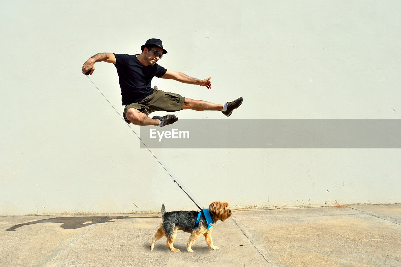 Man with dog jumping by wall