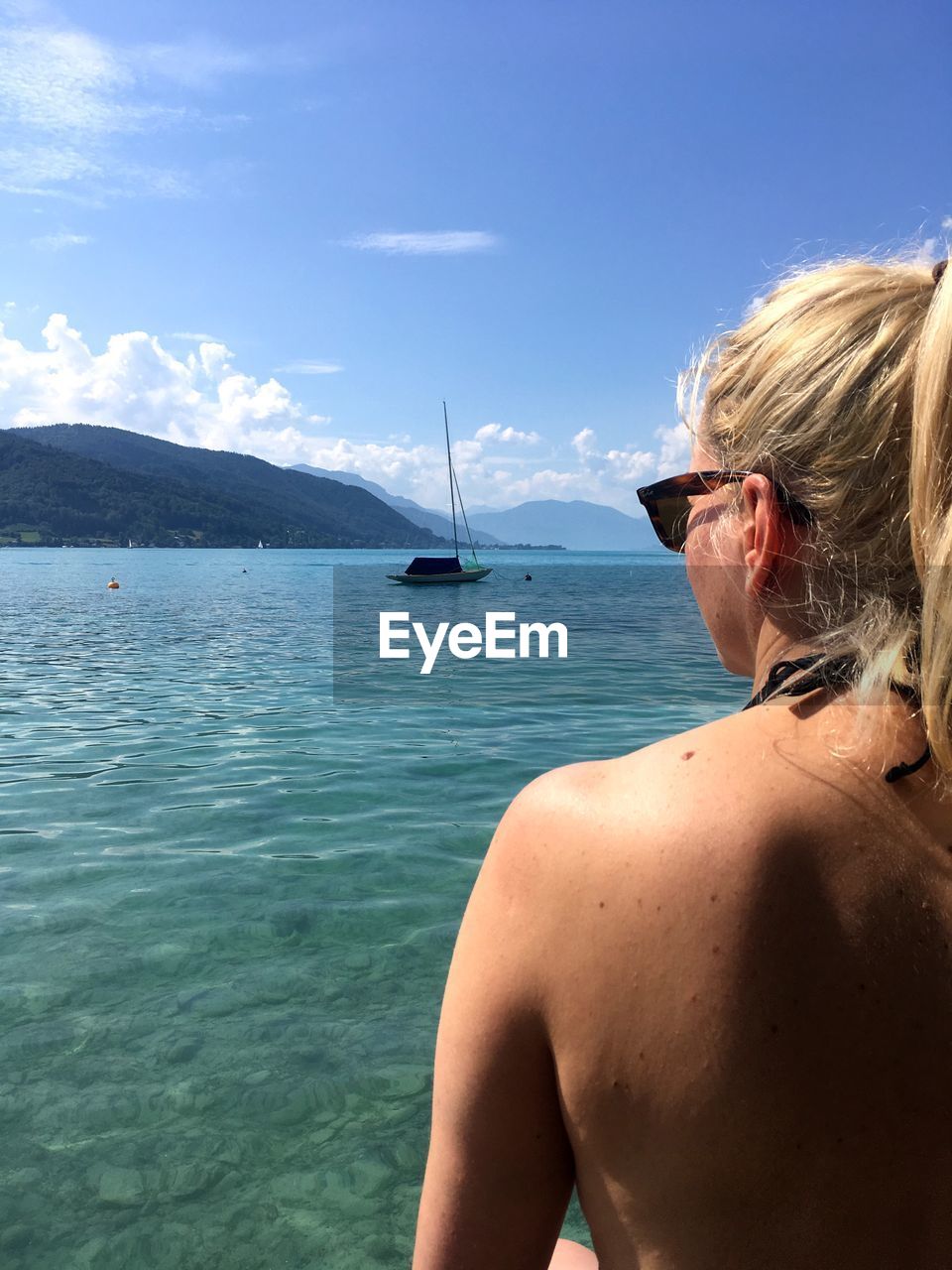 REAR VIEW OF WOMAN AT SEA AGAINST SKY