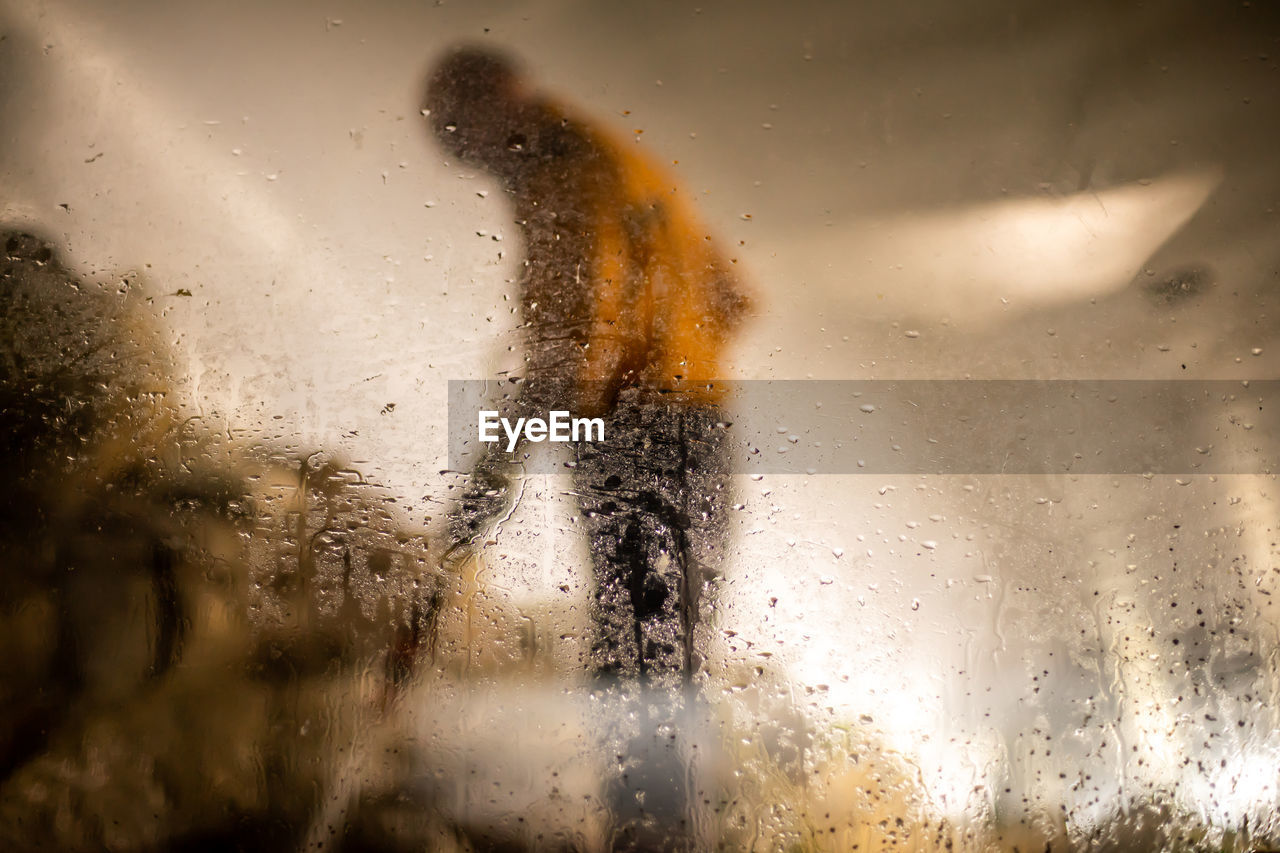Side view of man seen through wet car window during rainy season