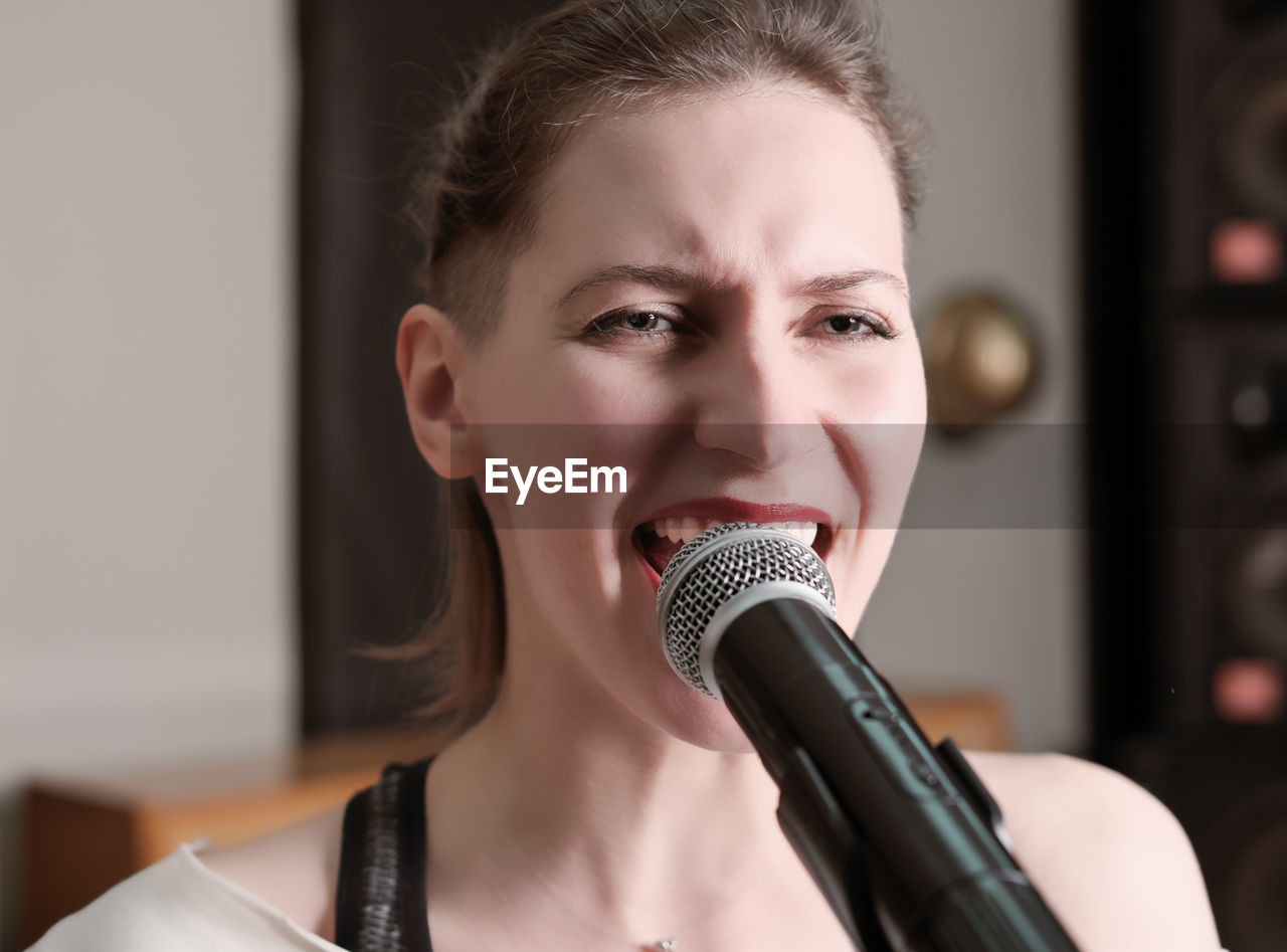 Young passionate woman singing in a microphone in a studio. vocal audio song recording. 