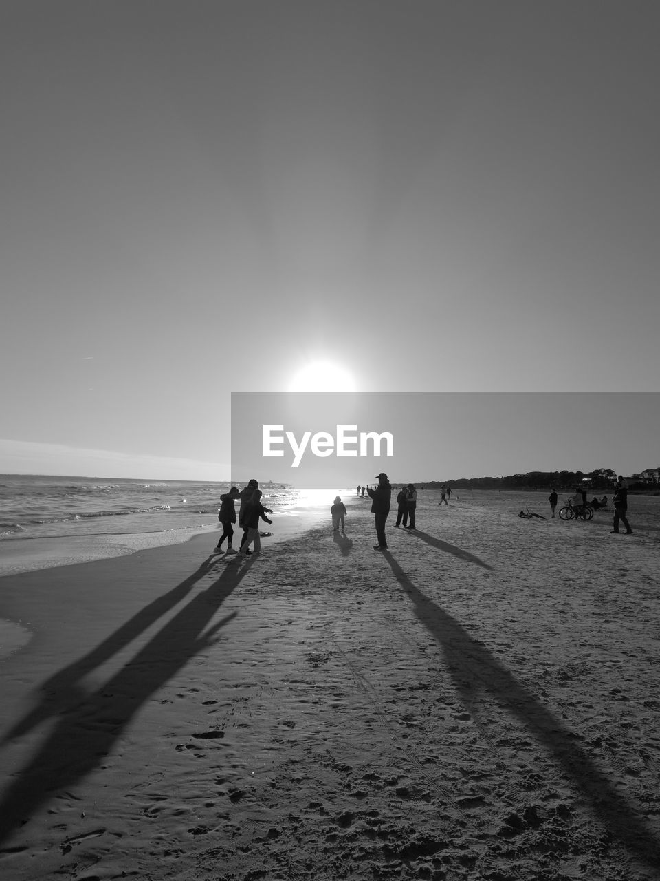 PEOPLE STANDING ON BEACH AGAINST CLEAR SKY