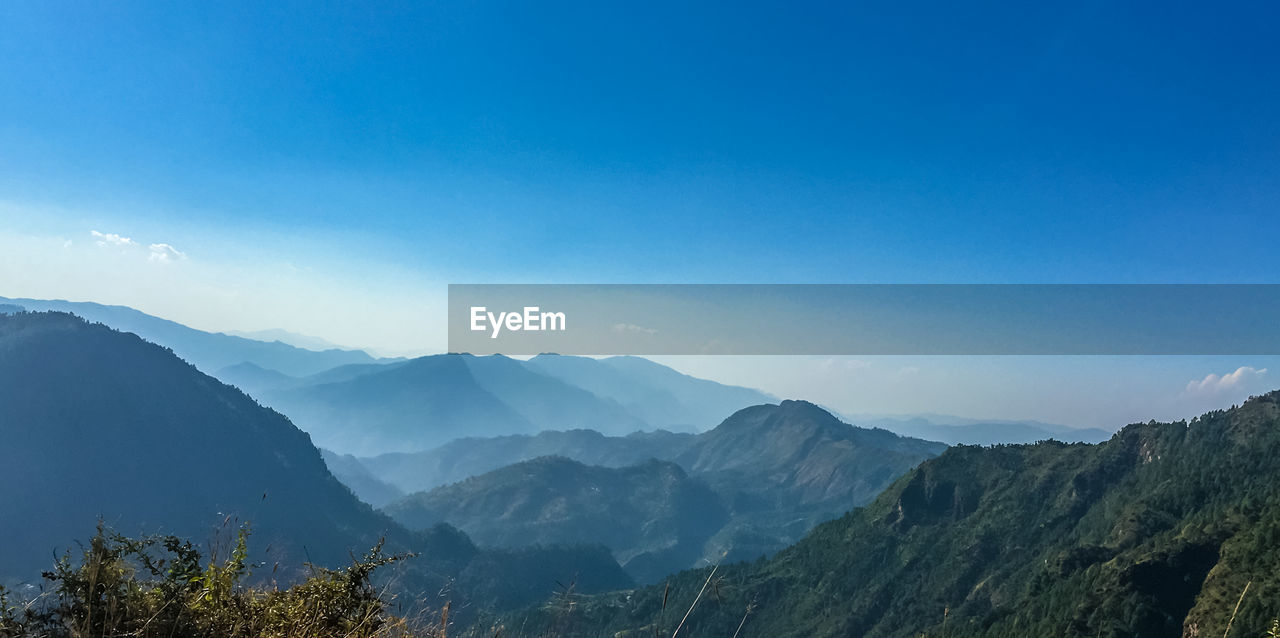 Scenic view of mountains against blue sky