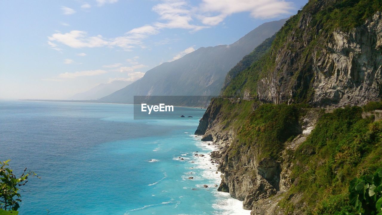 Scenic view of sea and mountains against cloudy sky