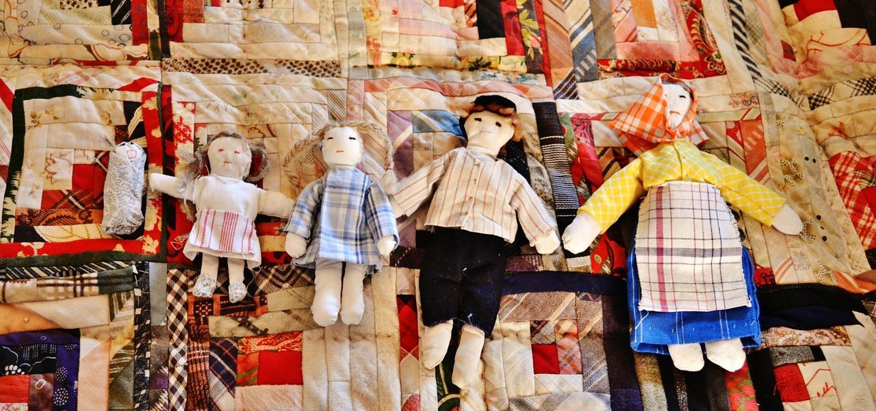 Five toy dolls on patchwork quilt