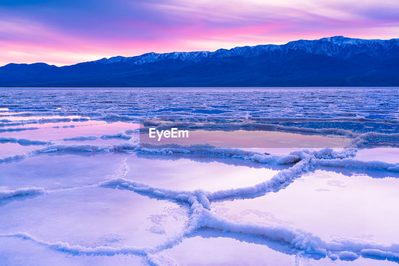 FROZEN LAKE AGAINST SKY DURING SUNSET