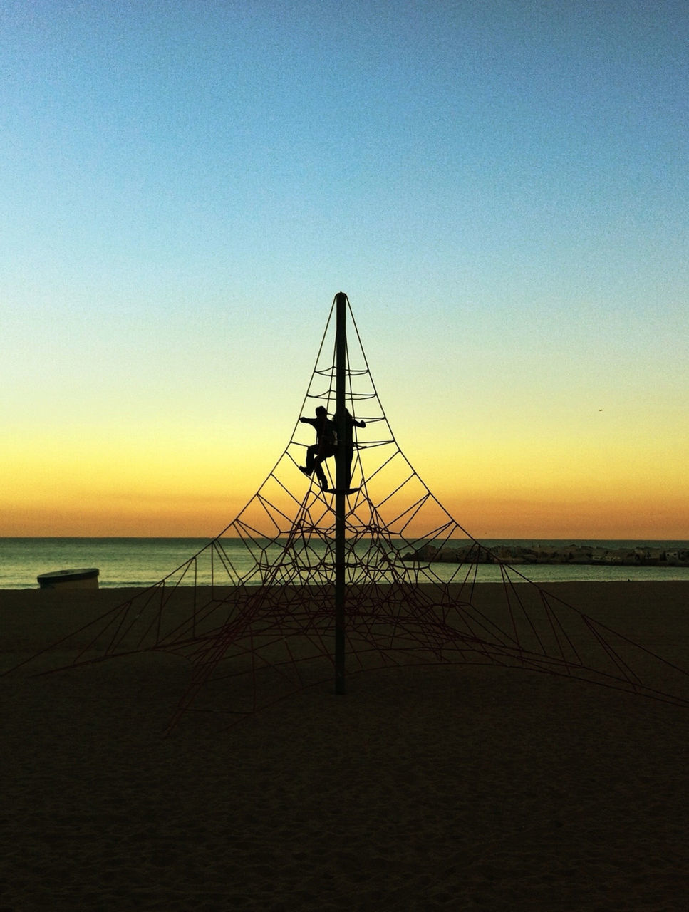 Silhouette couple climbing on rope in beach
