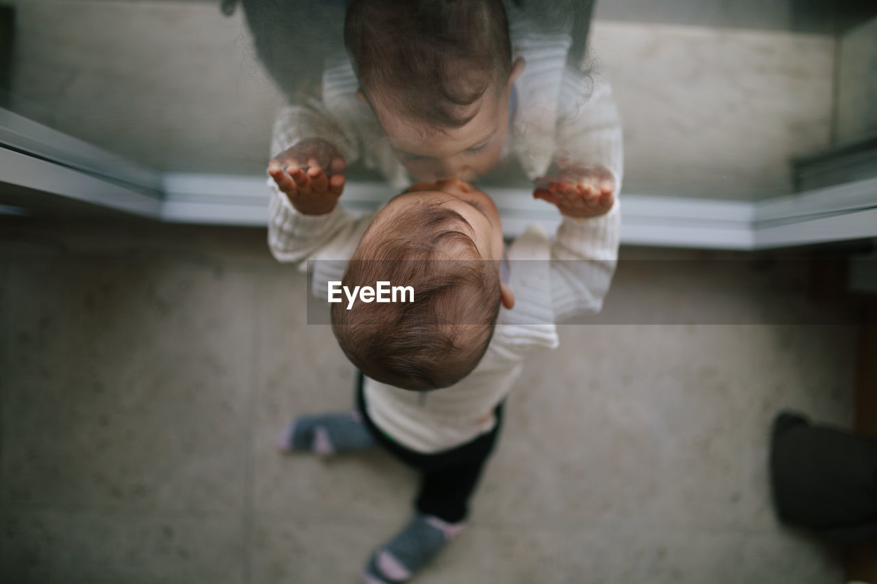 Directly above shot of baby boy leaning on glass window at home