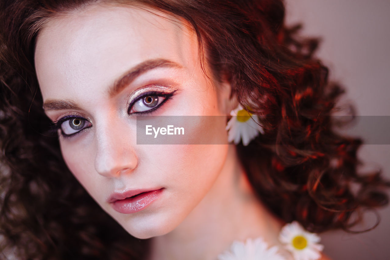 Close-up portrait of beautiful young woman wearing flowers and make-up